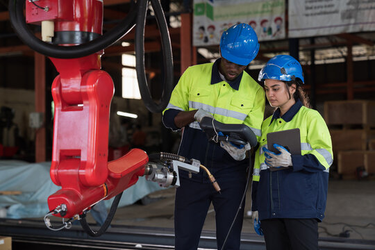 Male and female engineer repair autonomous robotics arm. Group of technician maintenance and control robotics arm in factory