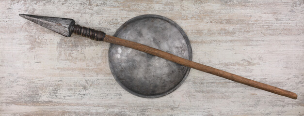 spear and iron shield on wooden background