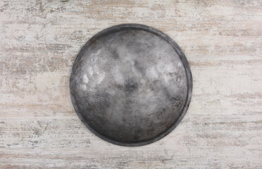 ancient round iron shield on wooden background