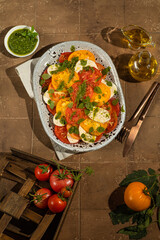 Caprese salad with yellow and red tomato on browm background. Italian cuisine. Top view