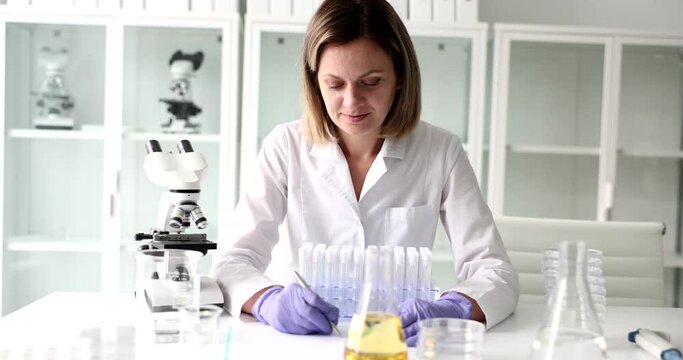 A contented woman, a scientist in the laboratory writes a close-up. Microscope and equipment certification