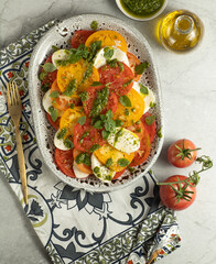 Caprese salad with yellow and red tomato on browm background. Vertical. Top view