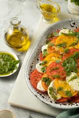 Close up of Caprese salad with yellow and red tomato on browm background. Italian cuisine.