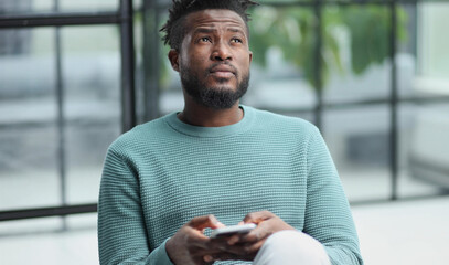 Black man looking at smartphone browsing internet, office technology and digital communication