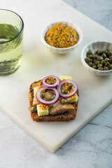 Scandinavian open sandwich with herrings on marble background. Vertical