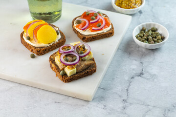 Three Scandinavian open sandwiches with herrings, salmon and potatoes on marble background. Copy...