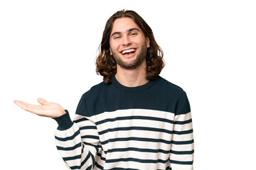 Young handsome man over isolated background holding copyspace imaginary on the palm to insert an ad