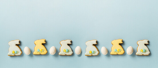 Easter border of gingerbread Easter bunnies and chocolate eggs on a pastel blue background with...