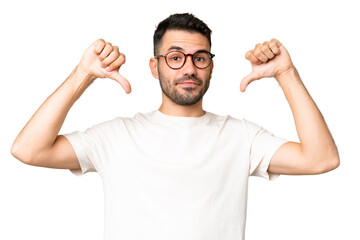 Fototapeta premium Young handsome caucasian man over isolated chroma key background showing thumb down with two hands