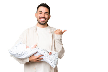 Young caucasian father with her newborn baby over isolated background pointing to the side to...