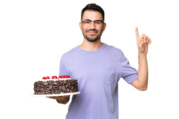Young caucasian man holding birthday cake isolated on green chrome background showing and lifting a...
