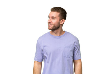 Fototapeta premium Young handsome caucasian man isolated on green chroma background looking to the side and smiling