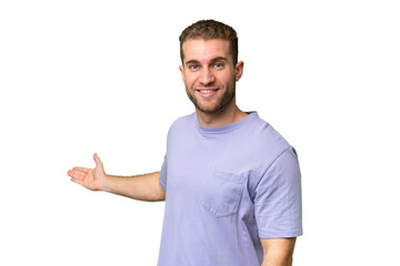 Young handsome caucasian man isolated on green chroma background extending hands to the side for inviting to come