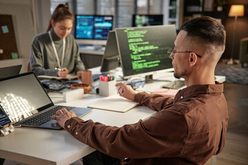 Pensive team lead answering e-mails and messages from coworkers on laptop