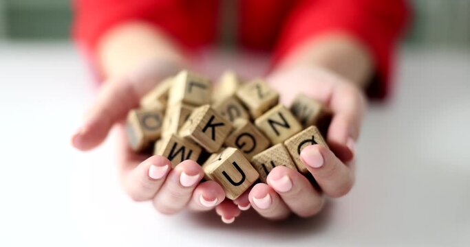 In the hands of a set of brown wooden blocks with letters, a close-up. Training in reading and writing