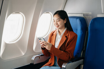 Young Asian executive excels in first class, multitasking with digital tablet, laptop and smartphone. Travel in style, work