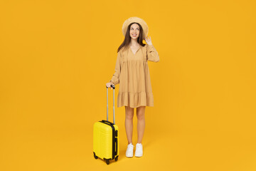 Young girl with a suitcase on a yellow background.