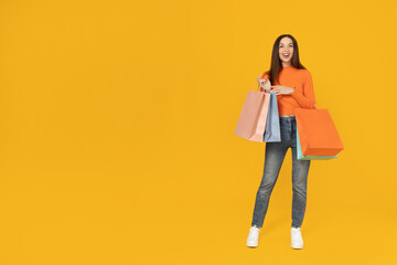 Young girl with shopping bags on a yellow background.