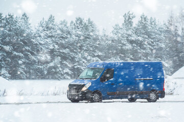 Van driving in the snow. Logistics on a snowy winter day. Delay of cargo delivery due to snowfall in winter. Side view of a commercial cargo van. - obrazy, fototapety, plakaty