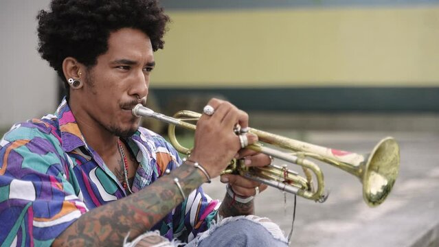 Trendy African American musician with tattoos and colourful aloha shirt playing trumpet