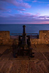 Sunset over the sea with a medieval cannon in the old town of Peniscola