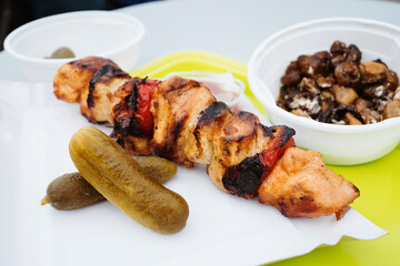 Traditional holiday market street food - chicken stewers with grilled mushrooms garlic and pickled cucumbers