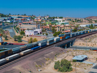 Panoramic view of a colorful freight train traversing a semi-arid Southwestern landscape with a...