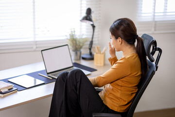 Business asian woman or accountant working on laptop computer with business document, graph diagram and calculator on home office table