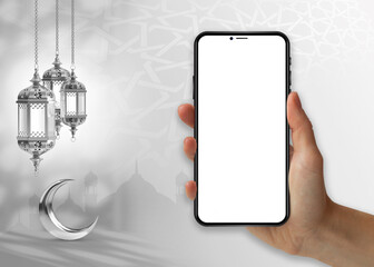 A hand holding a phone with a crescent moon and a crescent moon hanging on the wall islamic ramadan...
