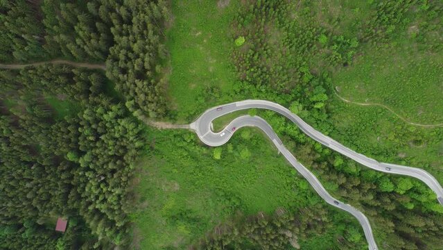 4K overhead drone shot of cars driving on a winding serpentine road. Route between Schladming and Ramsau am Dachstein, near Dachstein Glacier. Beautiful pine trees and alpine nature