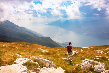 Hiker looking at panoramic view of lake Garda from a mountain