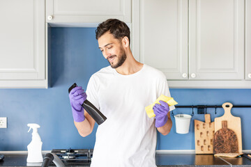 Funny man holding bottle spray and cleaning table. Household and housekeeping concept	