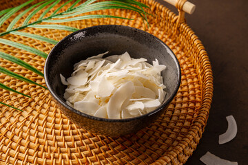 Dried coconut chips in a bowl on a dark background