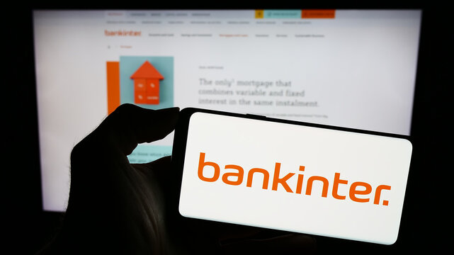 Stuttgart, Germany - 11-22-2023: Person holding cellphone with logo of Spanish financial services company Bankinter S.A. in front of business webpage. Focus on phone display.