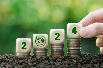 2024 New Year green business goal.Hand holding wooden block with 2024 on green background. Eco...