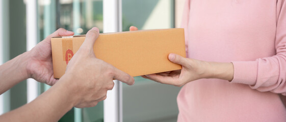 Obraz premium woman receives boxes parcel from courier in front house. Delivery man send deliver express. online shopping, paper containers, takeaway, postman, delivery service, packages