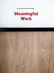 Wall background with direction sign to Meaningful Work - means work that gives sense of purpose,...