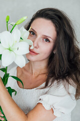 Beautiful brunette woman in white summer dress with beautiful flower