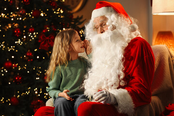 Fototapeta na wymiar Merry Christmas. Little girl whispering her wish to Santa at home, space for text