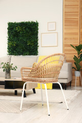 Green artificial plant wall panel and comfortable furniture in cozy living room. Interior design
