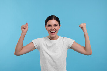 Naklejka premium Emotional sports fan celebrating on light blue background