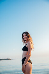 Beautiful slender woman in black swimsuit sunbathing on the beach