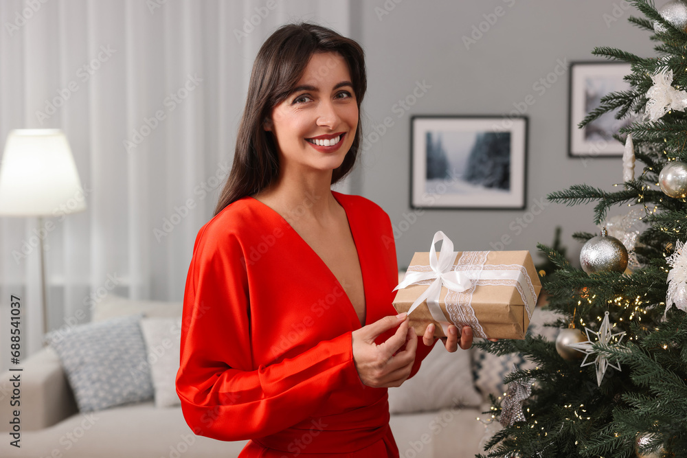 Wall mural Smiling woman opening Christmas gift at home