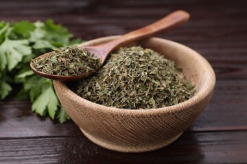Dried aromatic parsley and fresh leaves on wooden table, closeup