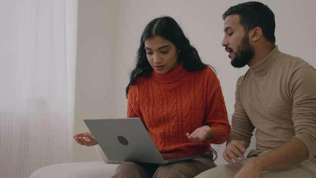 Upset young family arabic couple, wife  worried about resentment arabic man screaming waving her hands in anger, quarrel concept. Mixed race family using laptop and argue. Indian female with boyfriend