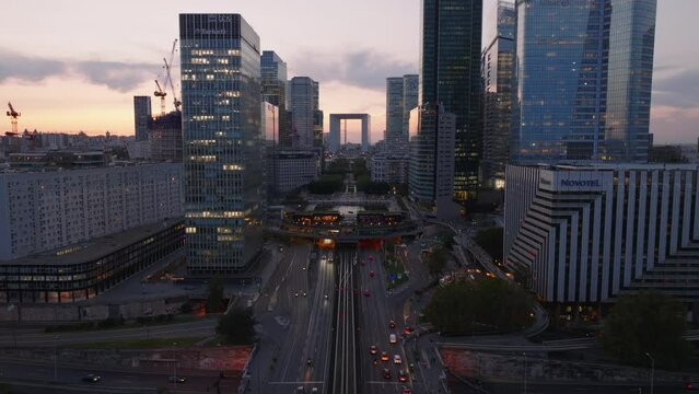Busy multilane road and tunnel under modern urban district at sunset. High rise office buildings in popular La Defense borough. Paris, France