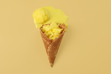 Melted ice cream in wafer cone on pale yellow background, top view