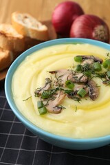Bowl of tasty cream soup with mushrooms, green onions and dill on table, closeup