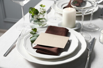 Beautiful table setting with blank card and floral decor indoors