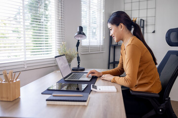 Young business asian woman work on laptop desk doing math finance on an office desk, tax, report,...